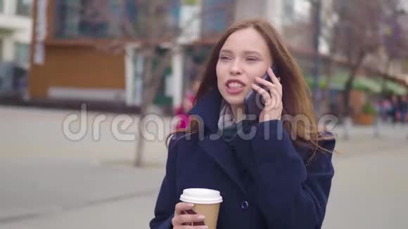 一位年轻漂亮的商业女学生穿着西装戴着眼镜在城市里走来走去喝着咖啡视频的预览图