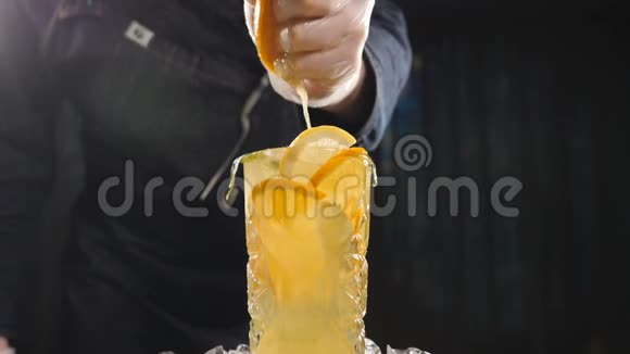 特写厨师将橙子以慢动作挤压到新鲜水果鸡尾酒上果汁从水果里滴出来烹调视频的预览图