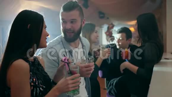 女孩和男孩在酒吧柜台附近用鸡尾酒交流背景是俱乐部里的一群朋友视频的预览图