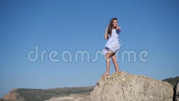 穿白衣服的女孩在晴朗的蓝天上摆姿势视频的预览图