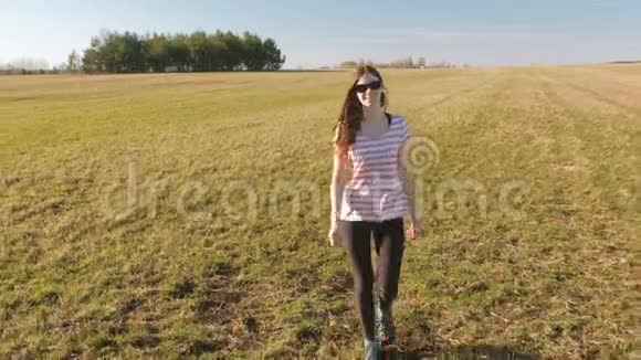 快乐的年轻女孩走在无尽的田野上美丽的夏日风景视频的预览图