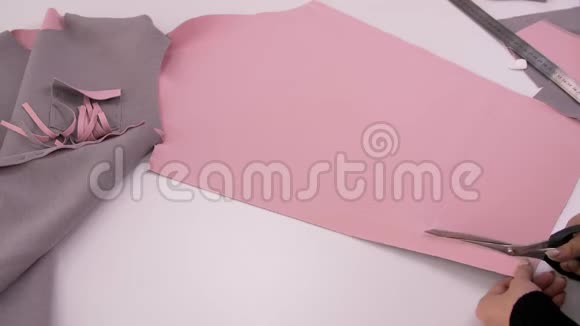 裁缝用剪刀剪粉红色的布料来缝制运动衫裁剪布料视频的预览图