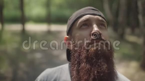 一个在森林里留着胡子和杯子的野蛮时髦男人的肖像视频的预览图