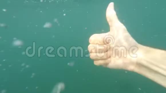 男性的手试图显示拇指向上标志手势在蓝色水下背景与气泡手势和手势身体视频的预览图