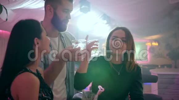 两个女孩和一个男人在俱乐部里玩得很开心手里拿着眼镜做祝酒词视频的预览图