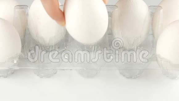 白色背景的透明塑料托盘中的大白鸡蛋女性的手把鸡蛋放在盘子里视频的预览图