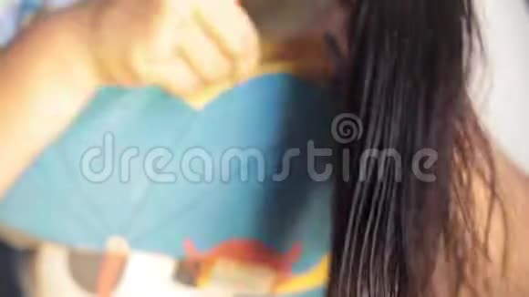 一个没有脸的年轻少女棕色头发梳理她的头发和干燥的头发视频的预览图