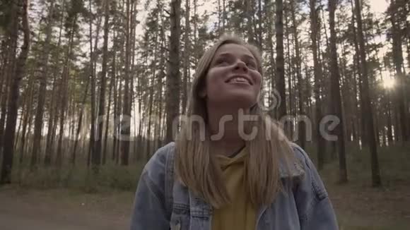 快乐的女孩站在阳光明媚的森林里微笑视频的预览图