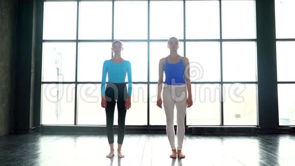 两个纤细的瑜伽女性在工作室练习伸展三角形姿势自然光年轻女性做瑜伽视频的预览图