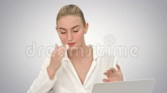女商人心情愉快地跳舞拿着笔记本电脑坐在桌子上在白色背景上接电话视频的预览图