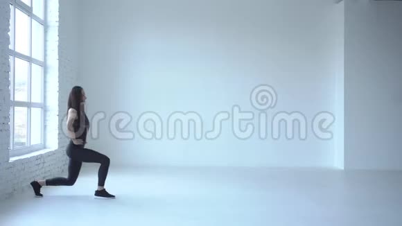 在白色的工作室里一位运动性运动的女子在表演行走的弓步4k视频的预览图