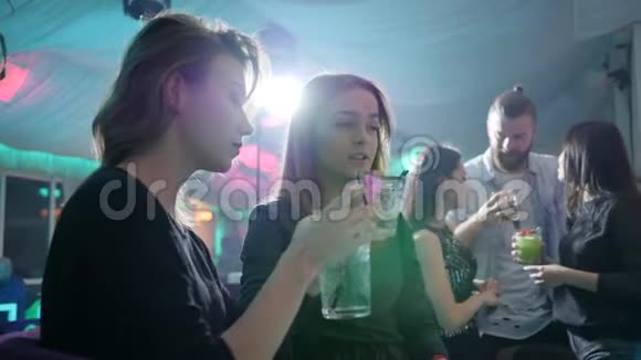 两位手里拿着鸡尾酒的年轻女性在酒吧柜台后面做烤面包背景是灯光视频的预览图