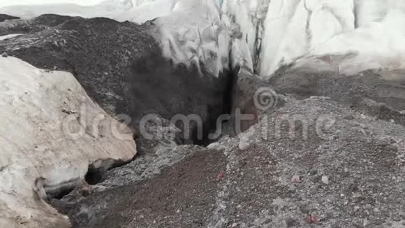 一位年轻的登山者戴着墨镜戴着帽子和棉条站在一座巨大的冰川上山脉上有巨大的裂缝视频的预览图