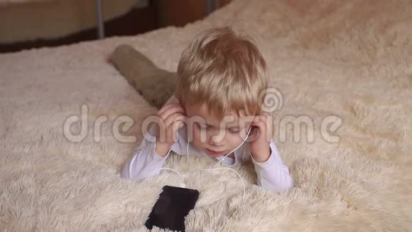 一个小男孩戴着耳机躺在床上视频的预览图