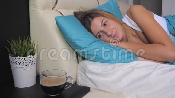女人在床上醒来想在床头柜上喝杯咖啡视频的预览图