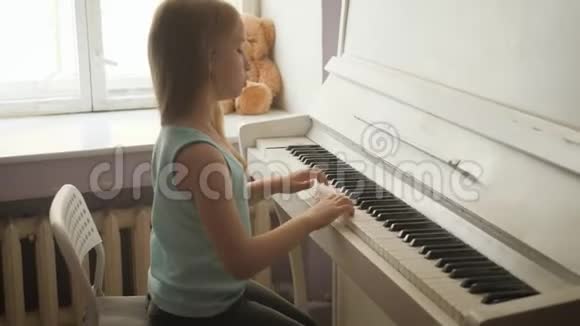 在家学习弹钢琴的小女孩学龄前儿童玩音乐乐器视频的预览图