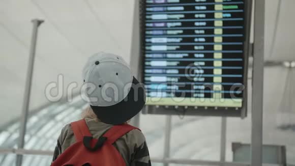 年轻背包客查看数字时刻表显示的飞行信息视频的预览图