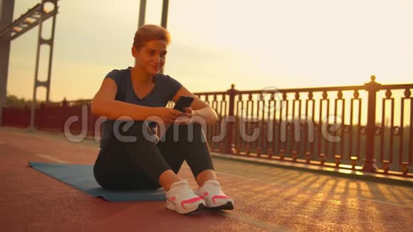 在桥上锻炼后使用手机的女孩视频的预览图