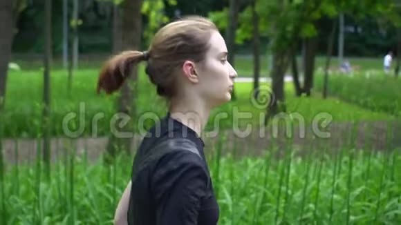 夏季在公园训练年轻女子短跑运动员草地绿背景慢动作视频的预览图