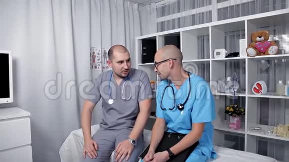 男医生和年轻实习生心情愉快地谈论新的医学研究视频的预览图
