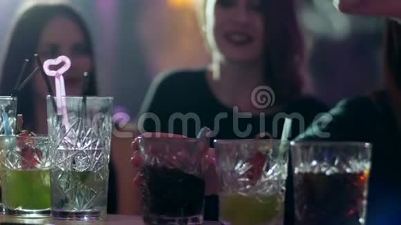青年朋友们在酒吧柜台上戴着眼镜在酒吧里放着五颜六色的鸡尾酒和吸管视频的预览图