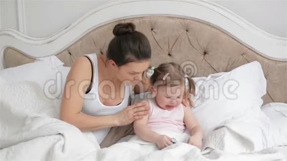 母亲正试图让女儿在卧室里安静下来给她的智能手机可爱的小女孩有两个马尾辫视频的预览图