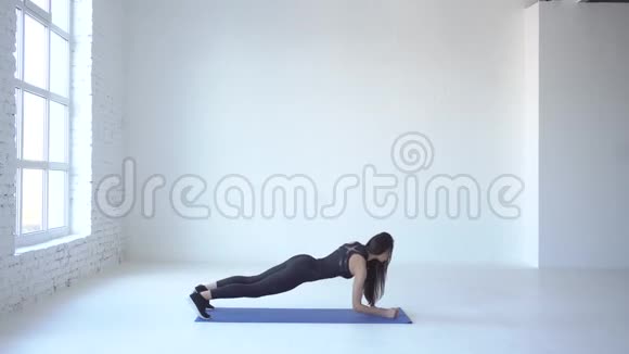 由年轻的运动女运动员在白色工作室的瑜伽垫上进行上下木板的运动4k视频的预览图