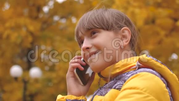 十几岁的女孩在秋天公园打电话微笑着视频的预览图