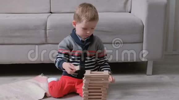 男孩正在用坐在沙发旁边的木块建造一座塔视频的预览图