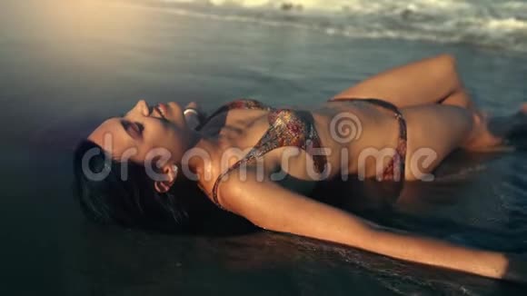 穿比基尼的年轻女孩躺在海边和日光浴视频的预览图