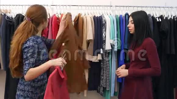 为客户服务的开朗的女售货员帮助在精品店的衣柜附近穿衣服视频的预览图
