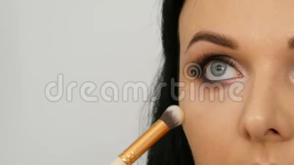 一位美丽的蓝眼女模特留着长长的黑发正在做傍晚的棕色眼妆和眉毛视频的预览图