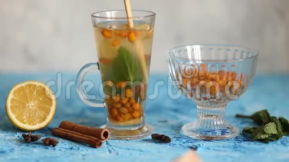 五颜六色的热沙棘茶与肉桂棒八角茴香和新鲜沙棘浆果视频的预览图