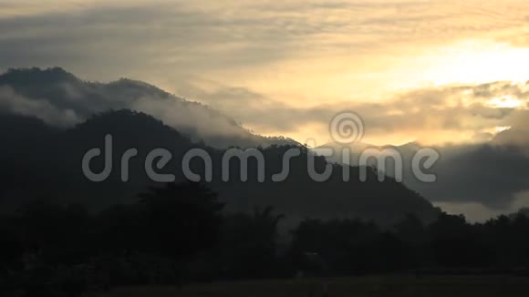 在泰国北部的梅红山金色的晨光和云彩飘过高大的山脉和茂密的森林视频的预览图