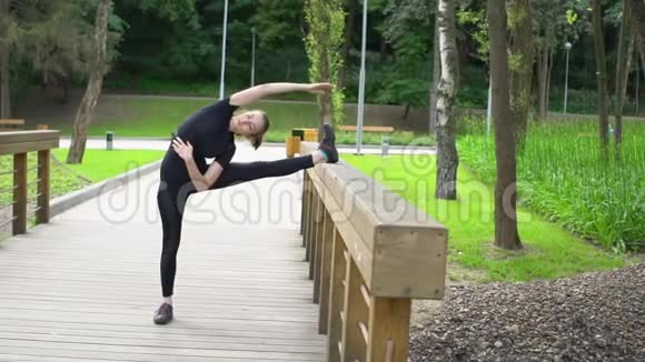 夏季在公园的木桥上进行伸展训练慢动作视频的预览图
