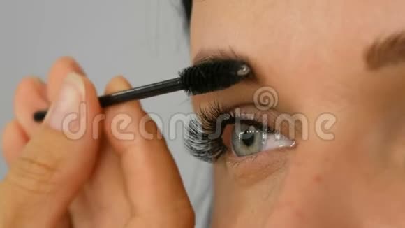 一位美丽的蓝眼女模特留着长长的黑发正在做傍晚的棕色眼妆和眉毛视频的预览图