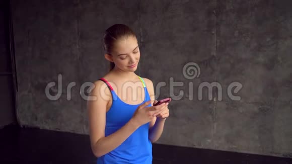 年轻健身女孩健身后使用手机健身房里一个带电话的女孩的特写快乐的肖像视频的预览图