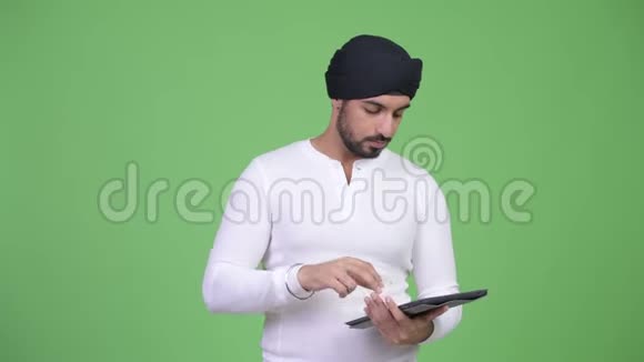 年轻的压力大留着胡子的印度男人使用数字平板电脑得到坏消息视频的预览图