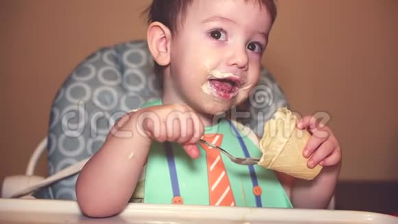 围兜里的孩子在华夫饼杯里吃了一勺冰淇淋看着镜头笑着宝宝脸是视频的预览图