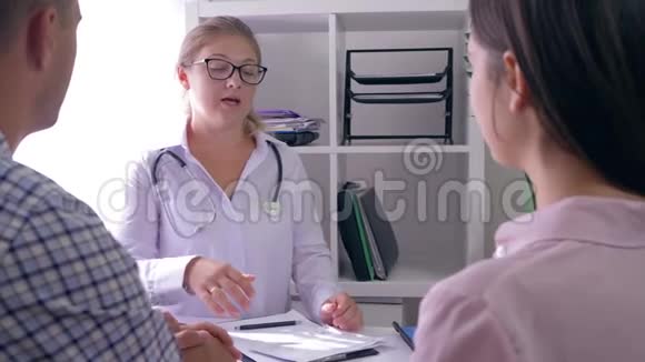 女医生和一对夫妇在生育诊所的医疗办公室谈论健康视频的预览图