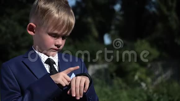穿着西装的小男孩在街上使用智能手表近距离射击视频的预览图