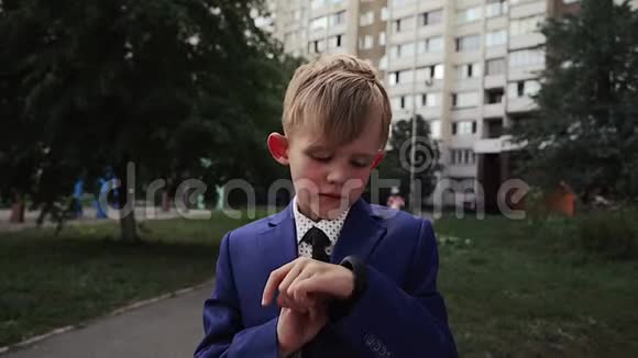在一个穿着商务服的小孩手上用黑色的表带合上智能手表的特写镜头运动智能手腕使用视频的预览图