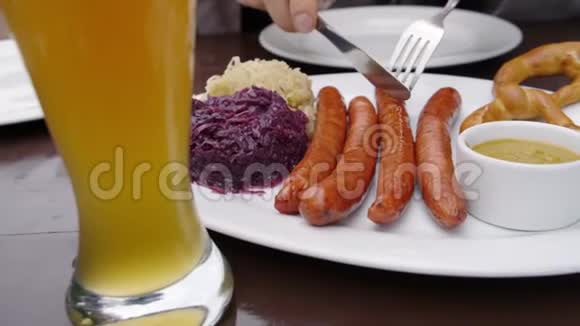 一个盘子里放着德国香肠和卷心菜旁边放着一杯啤酒客户把盘子放在他的盘子里关门视频的预览图