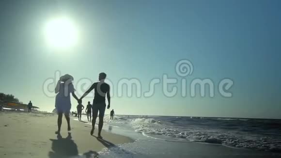 年轻漂亮的夫妇走在海边男孩和女孩他们很开心阳光灿烂慢动作他们跑了视频的预览图