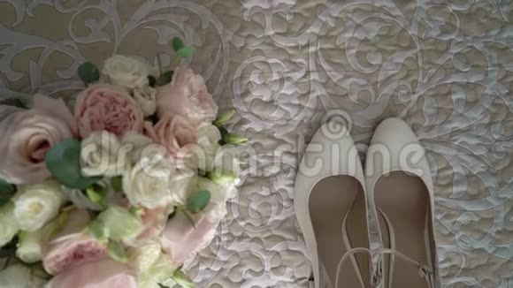 新娘配饰白色鞋子和新娘花束床上放着白色和粉红色的玫瑰视频的预览图