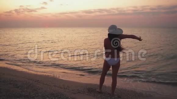 苗条的年轻女子正在日落时在海滩上跳舞视频的预览图