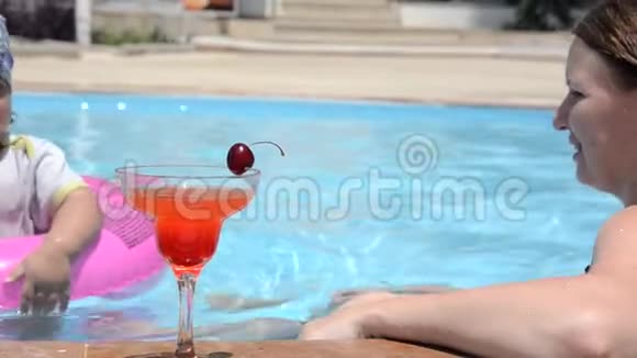 年轻女子穿着泳衣在杯中加入新鲜的西瓜或草莓喝杯鸡尾酒坐着喝一杯视频的预览图