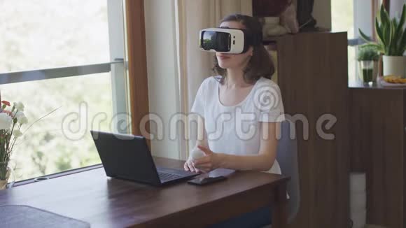 年轻女子坐在VR耳机上的笔记本电脑上视频的预览图