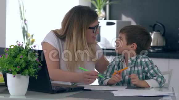 学前教育妈妈帮助儿子用彩色毡尖笔画坐在厨房里视频的预览图