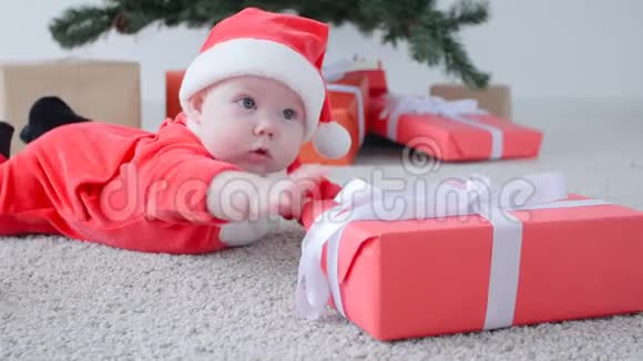 圣诞节的概念穿着圣诞老人服装可爱的宝宝看着礼物视频的预览图